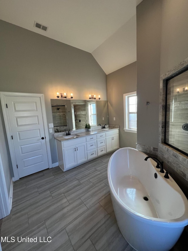 bathroom featuring lofted ceiling, shower with separate bathtub, and vanity