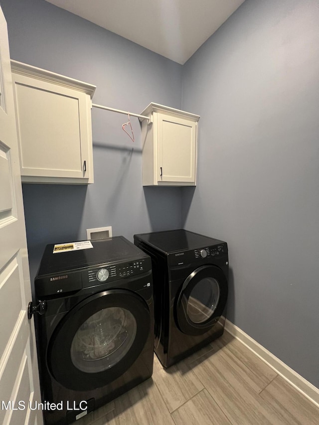 washroom with cabinets, independent washer and dryer, and light wood-type flooring