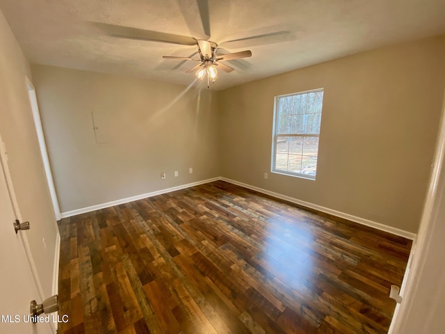 spare room featuring dark wood-style floors, ceiling fan, and baseboards