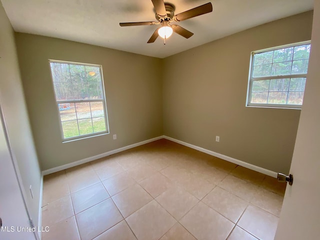 empty room with light tile patterned floors, ceiling fan, and baseboards