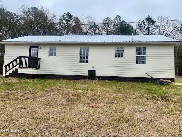 back of property featuring metal roof and a yard