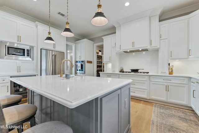 140 Seaside Dr, Ocean Springs, MS 39564 - kitchen with appliances with stainless steel finishes, a breakfast bar, light countertops, ornamental molding, and white cabinetry
