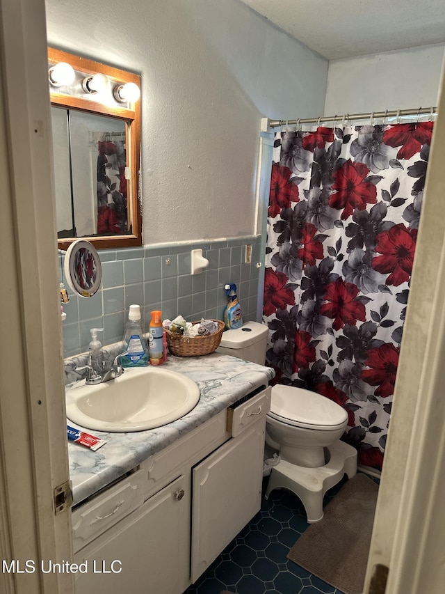 full bath with vanity, toilet, a wainscoted wall, tile walls, and a shower with curtain
