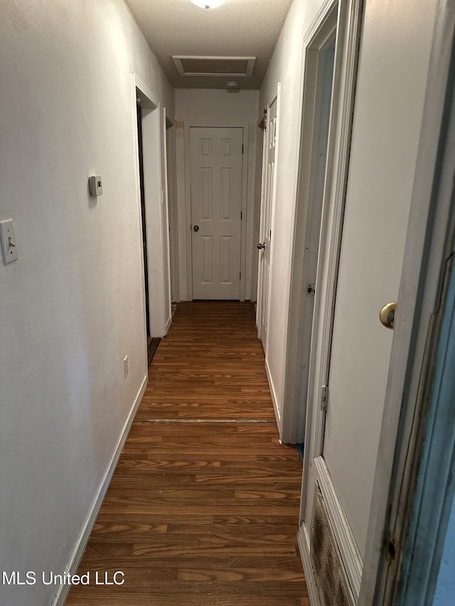 hallway with baseboards, attic access, and dark wood-style floors