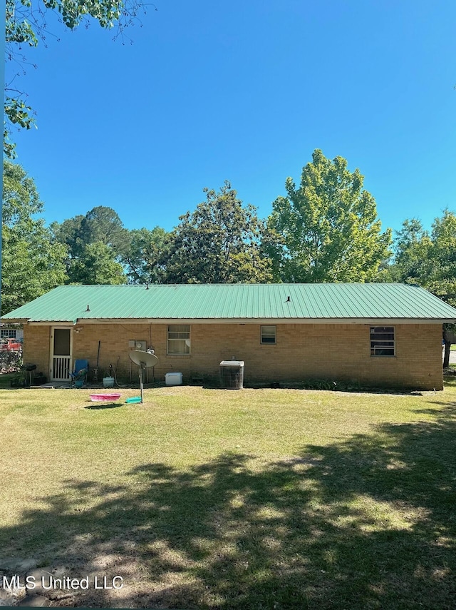 back of property with a yard, central AC, and metal roof