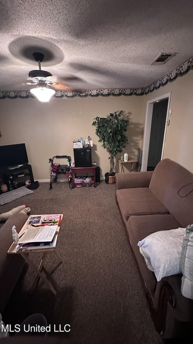 living room featuring carpet floors, a textured ceiling, ceiling fan, and visible vents