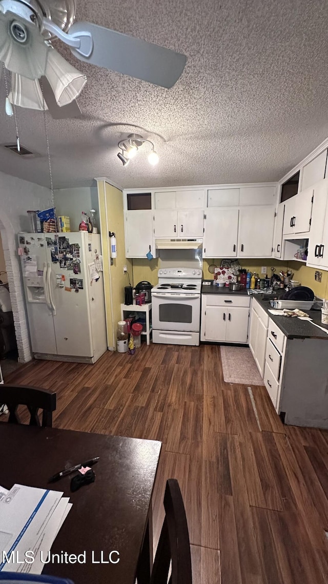 kitchen featuring dark countertops, white appliances, dark wood-style floors, a textured ceiling, and under cabinet range hood