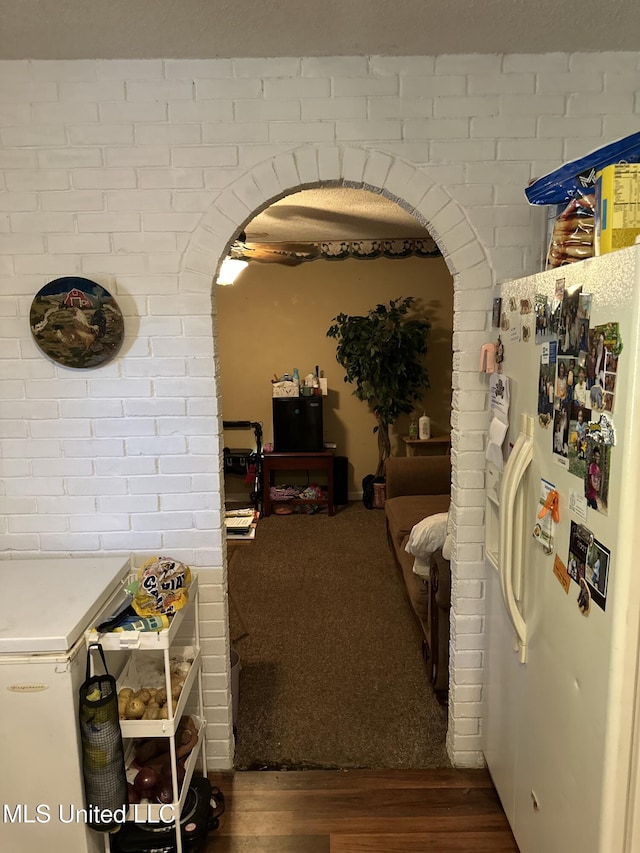 hall featuring arched walkways and wood finished floors