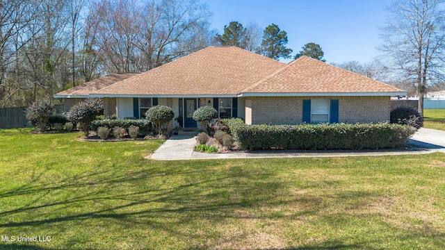 ranch-style house featuring a shingled roof, fence, a front lawn, and brick siding