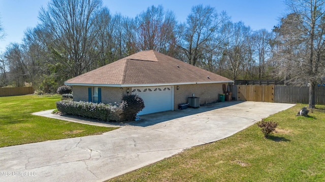 view of side of home with driveway, an attached garage, fence, a yard, and brick siding