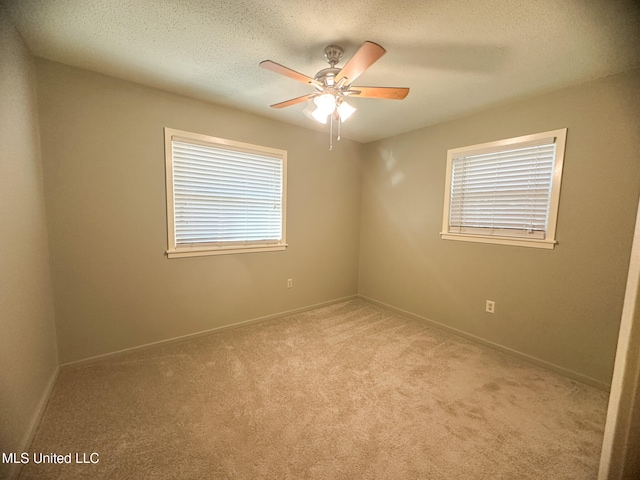 spare room with a textured ceiling, light colored carpet, plenty of natural light, and ceiling fan