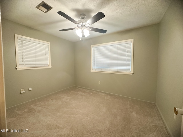 carpeted spare room featuring a textured ceiling and ceiling fan