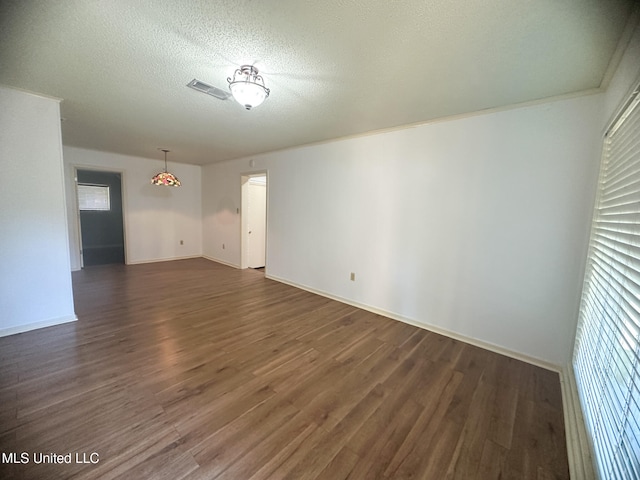 unfurnished room featuring dark wood-type flooring and a textured ceiling