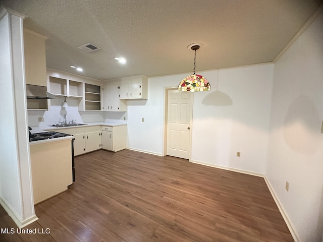 kitchen featuring a textured ceiling, dark hardwood / wood-style flooring, white cabinetry, wall chimney exhaust hood, and decorative light fixtures