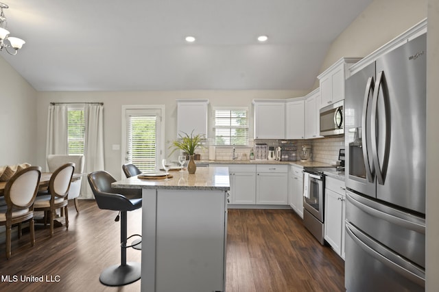 12 Mercer Dr, Petal, MS 39465 - kitchen with stainless steel appliances, lofted ceiling, tasteful backsplash, a kitchen island, and white cabinetry