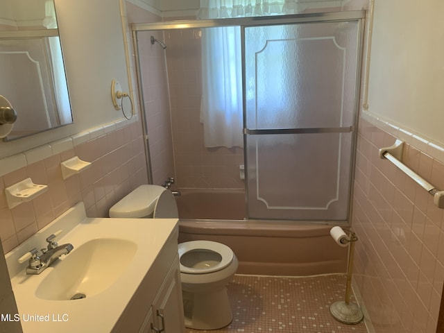 full bathroom featuring tile walls, wainscoting, toilet, and tile patterned flooring