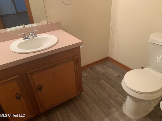 bathroom with baseboards, wood finished floors, toilet, and vanity