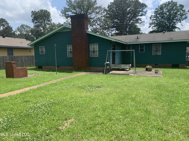 back of property featuring a chimney, a patio area, a lawn, crawl space, and fence