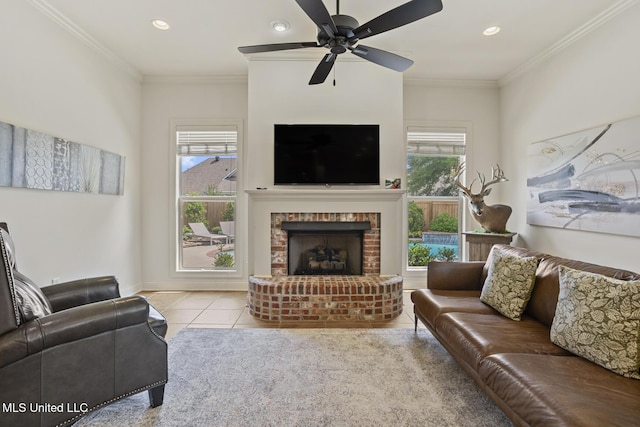 living area featuring a ceiling fan, a fireplace, tile patterned floors, recessed lighting, and crown molding