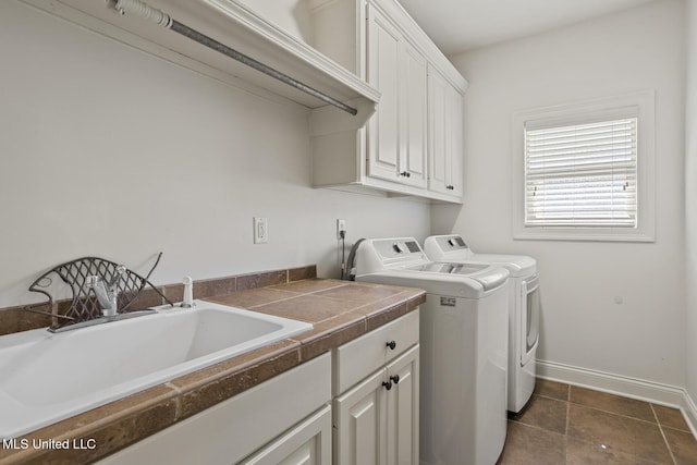 clothes washing area with cabinet space, washing machine and dryer, and baseboards