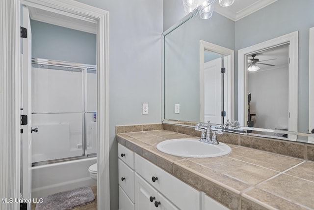 bathroom with toilet, crown molding, vanity, a ceiling fan, and shower / bath combination with glass door