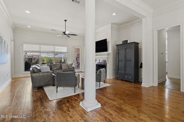 living area featuring ceiling fan, hardwood / wood-style floors, a high end fireplace, baseboards, and ornamental molding