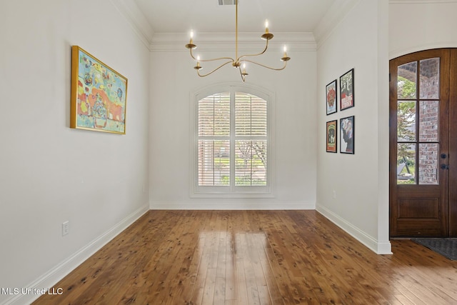 foyer with a chandelier, hardwood / wood-style floors, ornamental molding, and baseboards