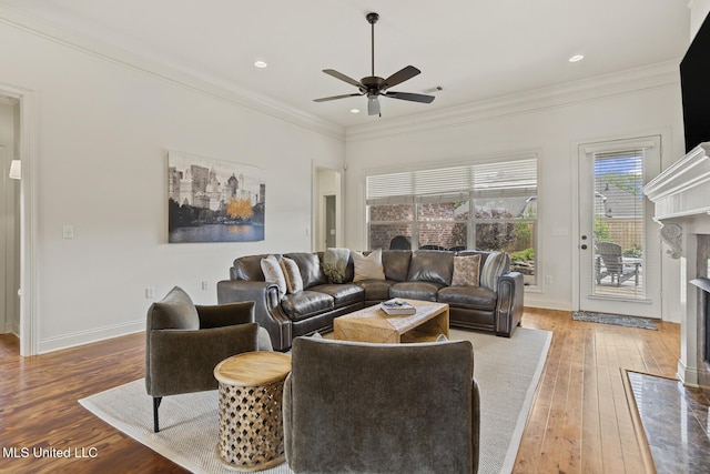 living area featuring a high end fireplace, ceiling fan, light wood-type flooring, crown molding, and baseboards