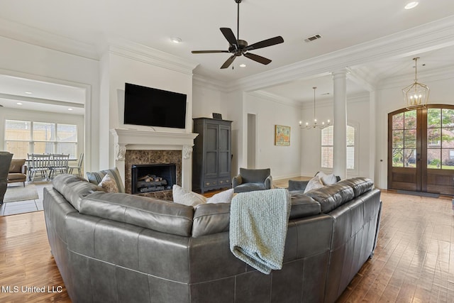 living room featuring french doors, a chandelier, wood finished floors, ceiling fan, and a premium fireplace