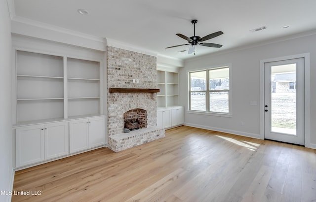 unfurnished living room with a wealth of natural light, built in features, light hardwood / wood-style flooring, and a fireplace