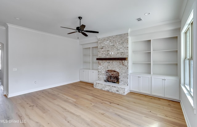 unfurnished living room featuring plenty of natural light, built in shelves, light wood-type flooring, and a fireplace