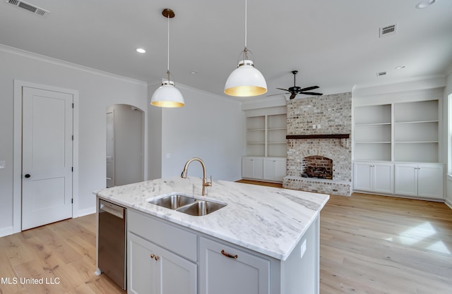 kitchen featuring dishwasher, hanging light fixtures, sink, built in features, and an island with sink