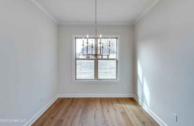 unfurnished dining area featuring light hardwood / wood-style flooring, ornamental molding, and an inviting chandelier