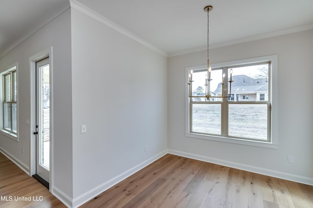 unfurnished dining area featuring wood-type flooring, ornamental molding, and an inviting chandelier