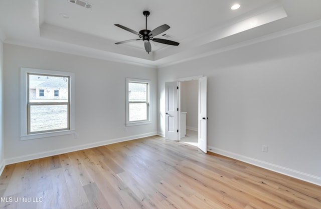 spare room featuring ceiling fan, a tray ceiling, crown molding, and light wood-type flooring