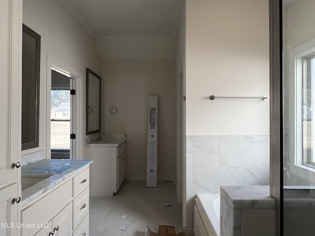 bathroom with vanity, a tub, lofted ceiling, and a healthy amount of sunlight