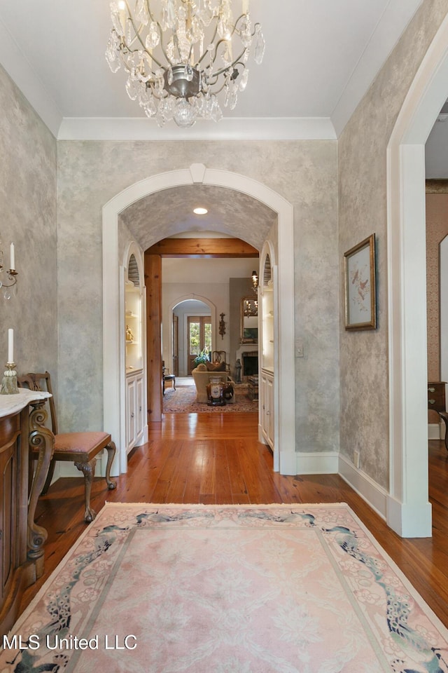 foyer featuring a chandelier, ornamental molding, and wood-type flooring