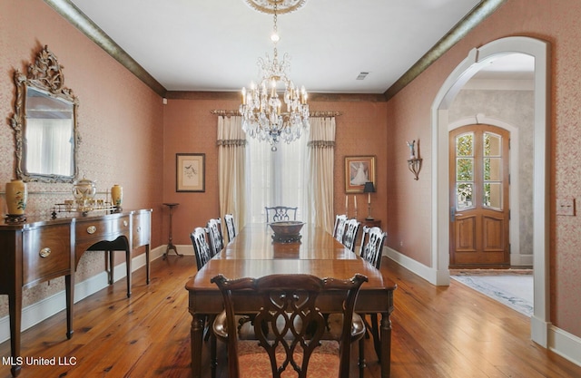 dining area with hardwood / wood-style floors, ornamental molding, and a chandelier