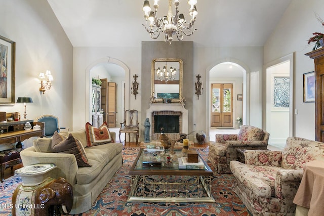 living room featuring vaulted ceiling, a brick fireplace, and an inviting chandelier