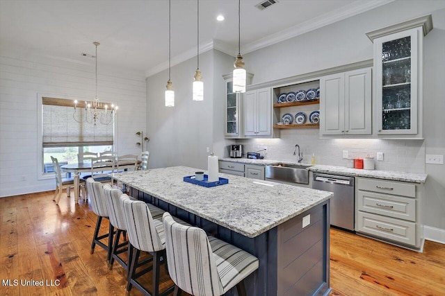 kitchen with a sink, ornamental molding, open shelves, and dishwasher