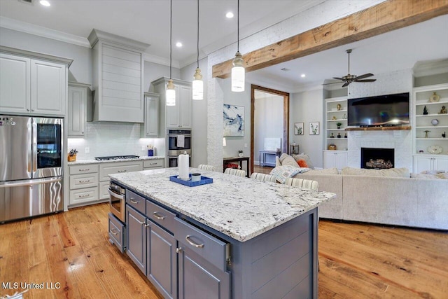 kitchen featuring crown molding, a kitchen island, ceiling fan, gray cabinets, and appliances with stainless steel finishes