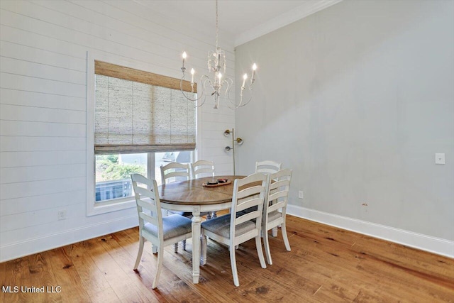 dining area featuring baseboards, an inviting chandelier, ornamental molding, and light wood-style floors
