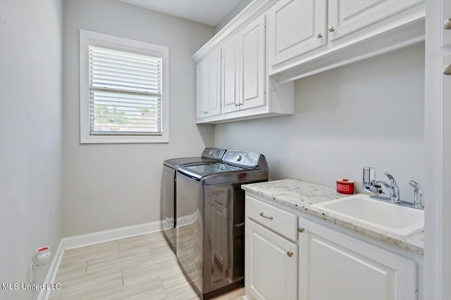 clothes washing area featuring a sink, baseboards, cabinet space, and washing machine and clothes dryer
