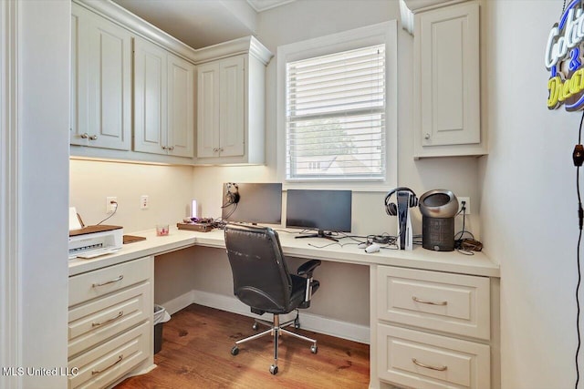 office featuring baseboards, built in desk, and wood finished floors
