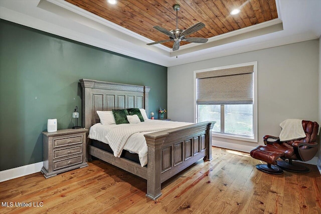 bedroom with crown molding, a raised ceiling, baseboards, and light wood-style floors