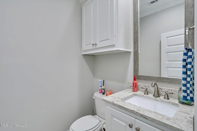bathroom featuring vanity, toilet, and visible vents