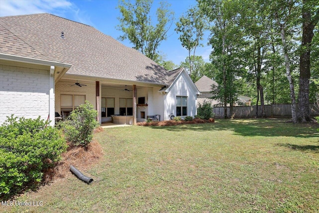 back of property featuring fence, a ceiling fan, a shingled roof, a patio area, and a yard