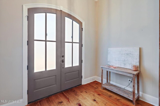 foyer entrance with baseboards, french doors, and wood finished floors