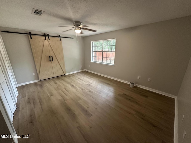 105 Poplar Dr, Brandon, MS 39047 - unfurnished bedroom featuring a barn door, wood finished floors, a textured ceiling, and a ceiling fan