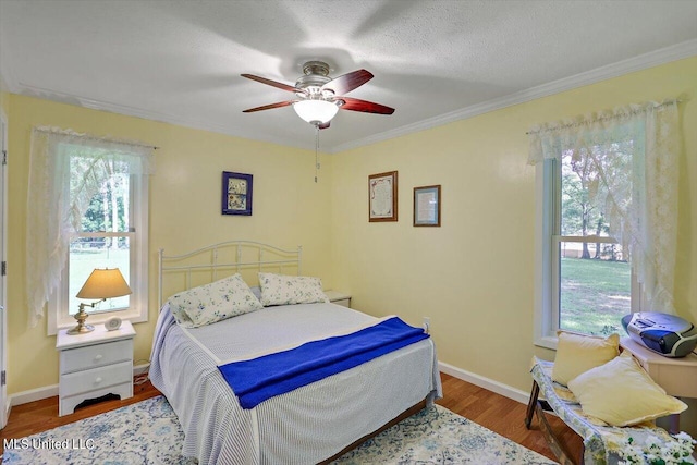 bedroom with ornamental molding, a textured ceiling, wood-type flooring, and ceiling fan